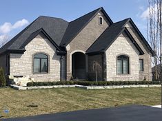 a large brick house with black roofing and two car garages on the driveway