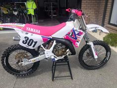 a pink and white dirt bike parked in front of a building