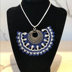 a necklace is displayed on a mannequin with blue and white beadwork