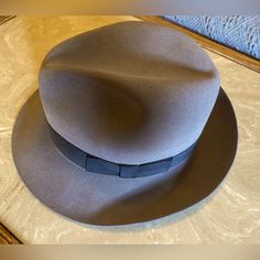 This Classic Turn Down Brim Fedora Is Made From Patented Gentlefelt, One Of The Most Comfortable 100% Wool Felt Formulas Ever Produced. The Wilton Fedora Is So Soft That It Literally Wraps Around Your Head, While Maintaining Its Shape Through Almost Any Mishap, Including Rain, Jostling And Getting Folded Under Heavier Objects. This Was A Gift And Never Worn. Made Of A Fur Blend That's Water Resistant. 100% Wool Gentlefelt. Hand Wash Only. Country Gentleman. Packable, Water Repellent, Grosgrain B Classic Gray Fedora With Curved Brim, Classic Gray Hat Bands With Flat Brim, Classic Gray Flat Brim Hat Band, Classic Gray Flat Brim Hat, Classic Gray Hat With Short Brim, Classic Gray Wide Brim Fedora, Classic Gray Fedora Hat, Classic Gray Wide Brim Felt Hat, Classic Gray Brimmed Hat