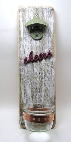 a mason jar with the word cheers hanging on it's side, in front of a wooden sign