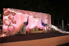 a decorated stage with two peacocks on it and flowers all around the stage area