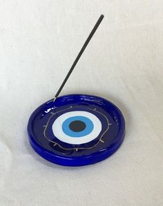 a blue plate with an evil eye on it and a black stick sticking out of the center