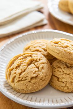 three cookies on a white plate sitting on a wooden table