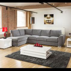 a living room filled with furniture on top of a hard wood floor covered in grey rugs