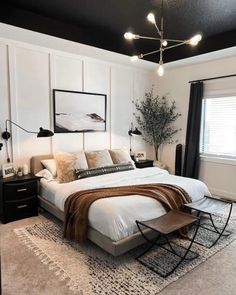 a bedroom with white walls, black ceiling and carpeted flooring that has a large bed in it