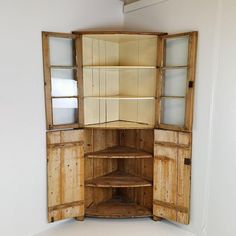 an open wooden cabinet with glass doors and shelves in the center, on top of a white floor