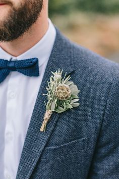 a man wearing a blue bow tie and a boutonniere