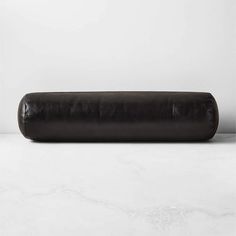 a roll of black leather sitting on top of a white counter next to a wall