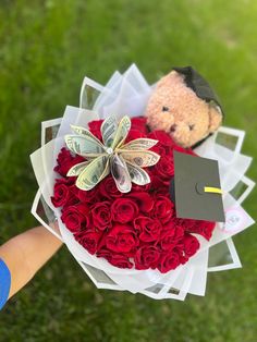 someone is holding a bouquet of roses and a teddy bear in the background with a graduation cap on it