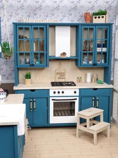 a blue and white kitchen with wooden floors, cabinets, stove top oven and stool