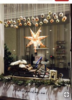 a christmas display in a store window with ornaments hanging from the ceiling and lights on the windowsill