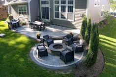 an outdoor patio with chairs and fire pit in the middle, surrounded by green grass