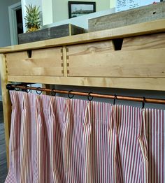 a kitchen counter with red and white striped curtains hanging from it's side rail