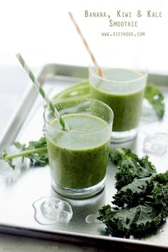 two glasses filled with green smoothie on top of a metal tray