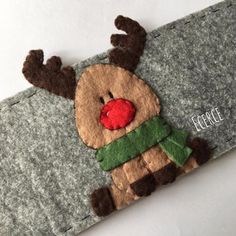 a felt reindeer with a red nose and green scarf on it's head is shown