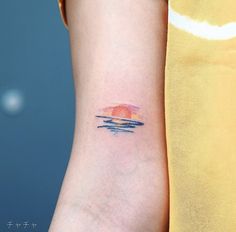 a woman's arm with a small sunset tattoo on the left side of her arm