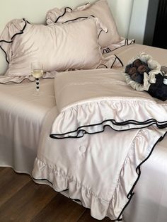 a bed with white sheets and black ruffles on the bottom, along with two champagne flutes