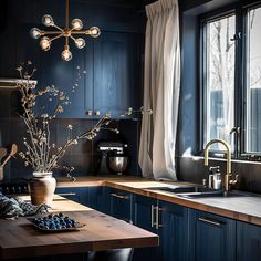 a kitchen with dark blue cabinets and wooden counter tops, an overhead light fixture hangs over the sink