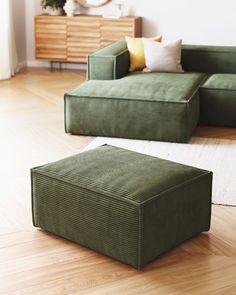 a green couch sitting on top of a hard wood floor next to a white rug