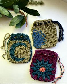 three crocheted purses sitting next to each other on a white counter top