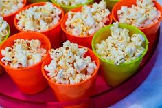 small cups filled with popcorn sitting on top of a pink tray next to each other