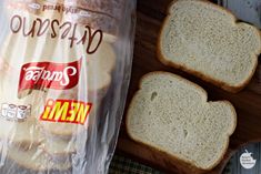 two slices of bread sitting on top of a cutting board next to a bag of chips