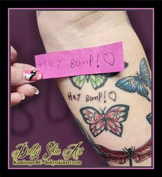 a woman's arm with butterfly tattoos and a pink sticky note attached to it