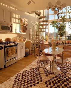 a kitchen with a spiral staircase leading up to the second floor and a dining area