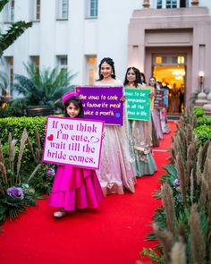 some girls are holding signs on a red carpet