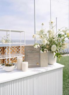 a table with flowers and candles on it in front of an ocean side fenced area