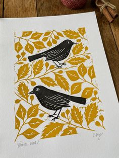 two black birds sitting on top of yellow leaves