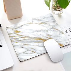 a white and gold marble mouse pad sitting on top of a desk next to a keyboard