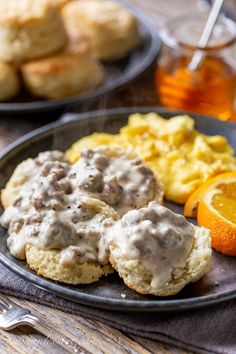 biscuits with gravy and an orange on a plate next to other breakfast foods