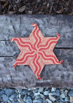 a red and white star ornament sitting on top of a piece of wood