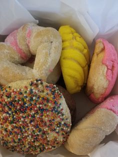 several different types of doughnuts in a paper bag with sprinkles