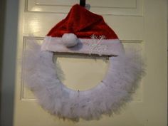 a white wreath with a santa hat hanging on the front door