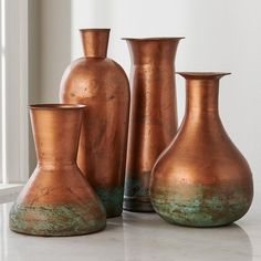 three copper vases sitting next to each other on a table