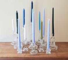 several candles are lined up on a table with clear glass vases and candle holders