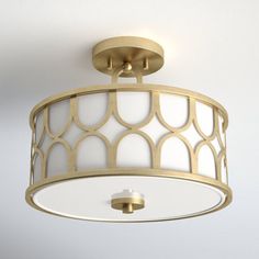 a white and gold ceiling light with an intricate design on the top part of it