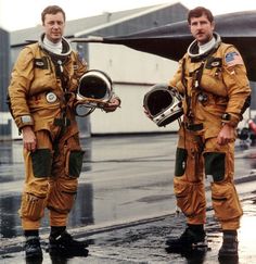 two men in yellow spacesuits standing next to each other on an airport tarmac