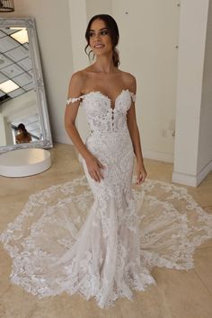 a woman in a white wedding dress standing on the floor with her hands on her hips