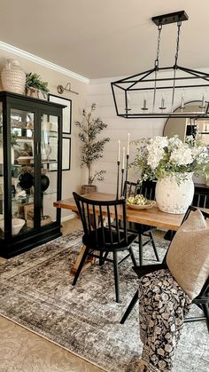 the dining room table is surrounded by chairs and vases with flowers on them,