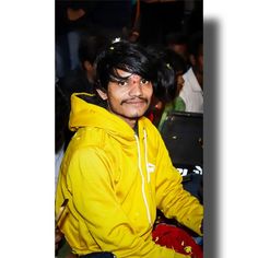 a man in a yellow hoodie sitting down