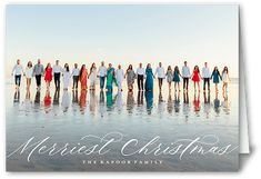 a group of people standing on top of a beach next to the ocean with an advertisement