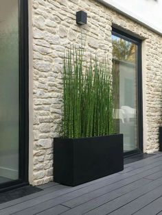 a black planter sitting on top of a wooden floor next to a building with windows