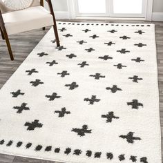 a white rug with black crosses on it in front of a chair and door way