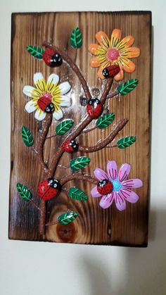 a wooden plaque with flowers and ladybugs painted on it