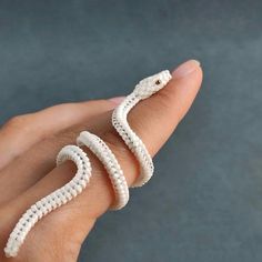 a hand holding a white beaded snake ring