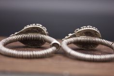 Silver ear ornaments. The hoops are made of pearled wire and the bezel is decorated with Turquoise. Excellent workmanship with a great patina for its age. This particular design is worn in pairs by women from Kham in East Tibet. These pieces might have been handed down to generations. *wear and tear as per age, intact. Weight: 28 grams Ring Size: 34mm Origin: Early 20th c Tibet Traditional Silver Oval Earrings, Silver Spiral Earrings For Wedding, Handmade Vintage Hoop Earrings For Wedding, Traditional Nickel-free Wedding Jewelry, Silver Spiral Wedding Earrings, Traditional Teardrop Hoop Earrings Nickel Free, Traditional Nickel-free Hoop Earrings For Wedding, Vintage Handmade Hoop Earrings For Wedding, Vintage Silver Hoop Earrings For Wedding